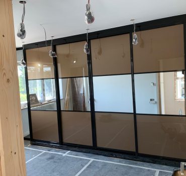 Black-framed wardrobe with bronze-tinted sliding glass doors - Dreamline Interiors
